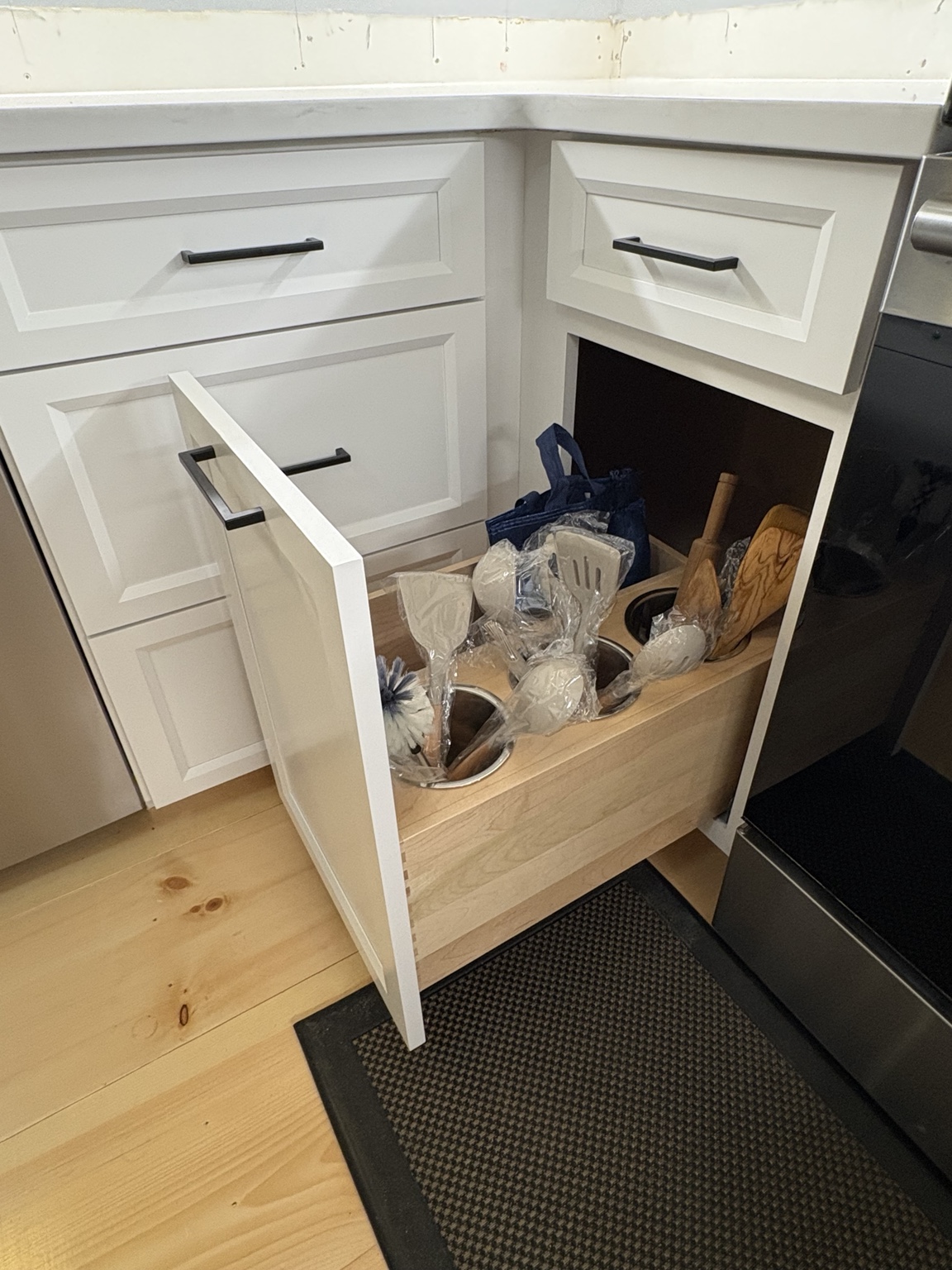 White kitchen cabinet with a pull-out organizer for utensils and cookware