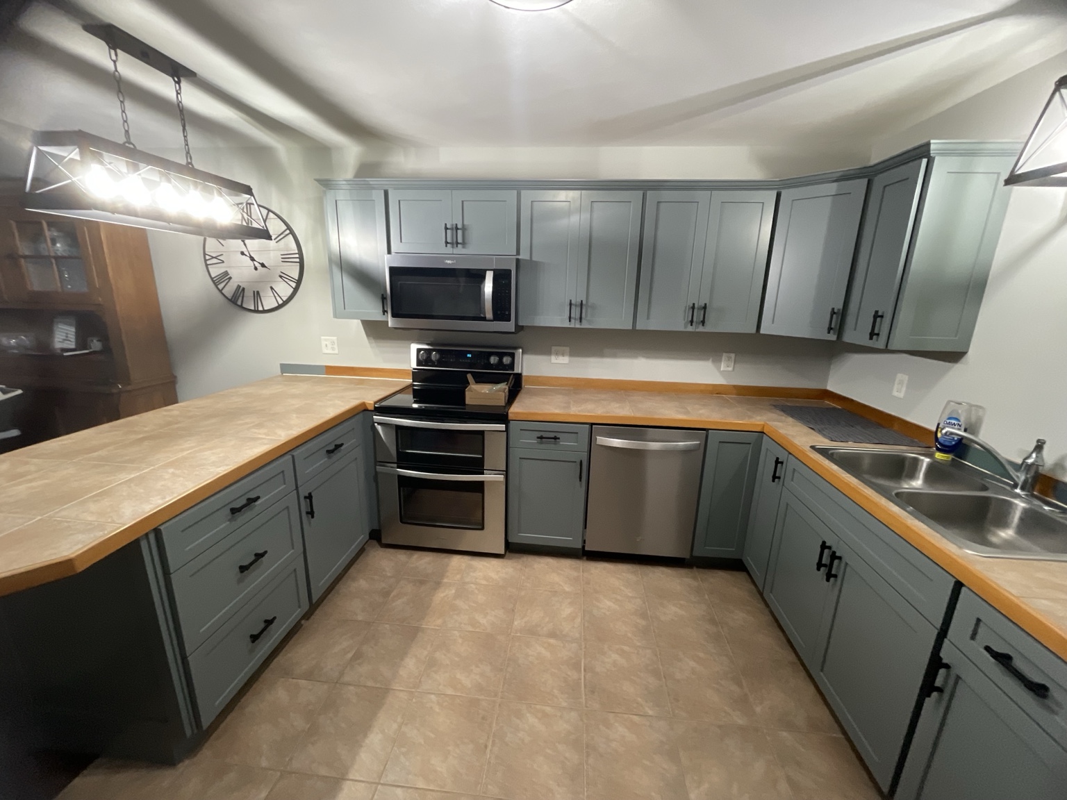 Kitchen after cabinet refacing, with updated blue-gray cabinet fronts and black hardware