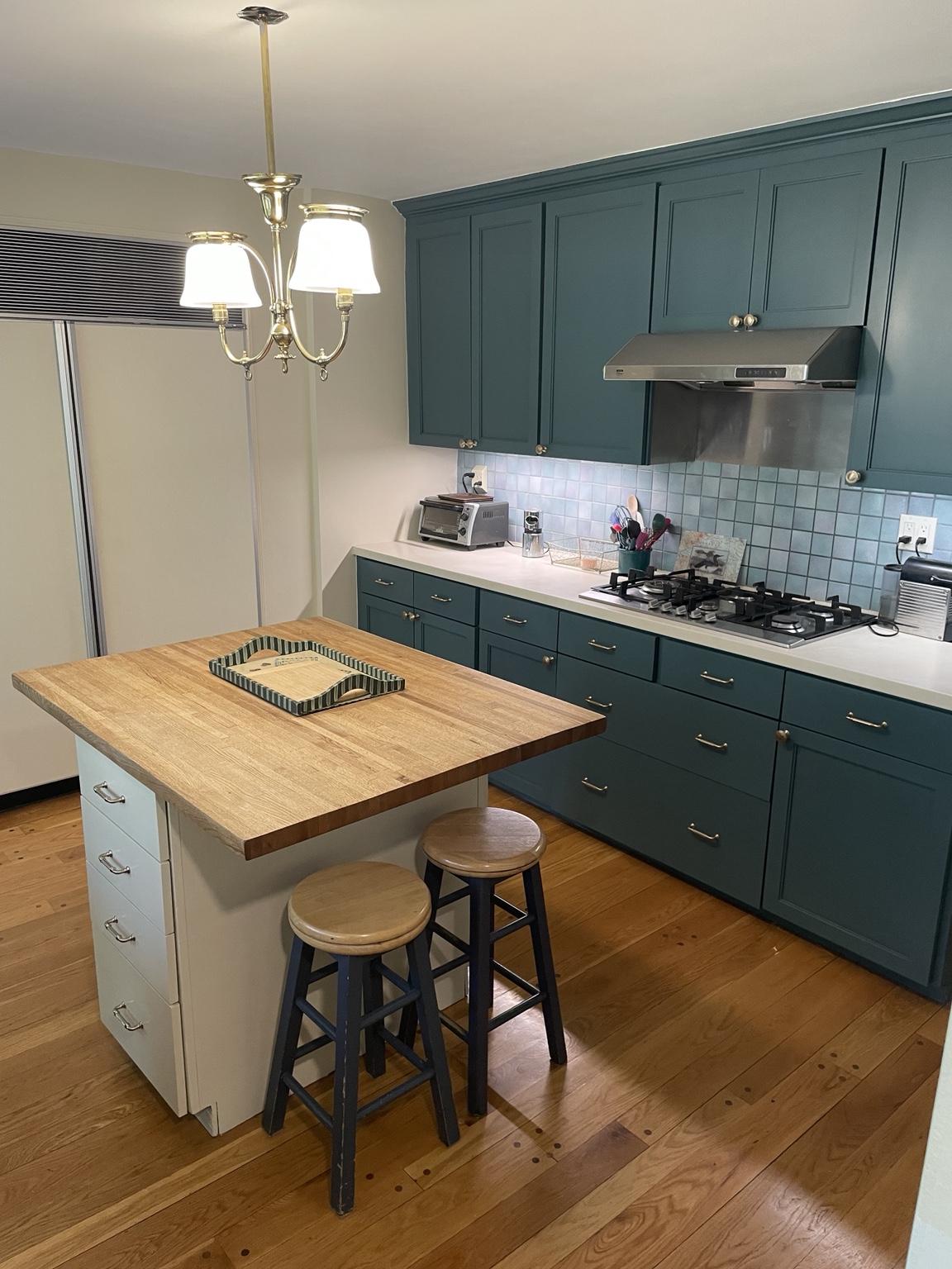 Kitchen with deep teal refinished cabinets and a wood island top